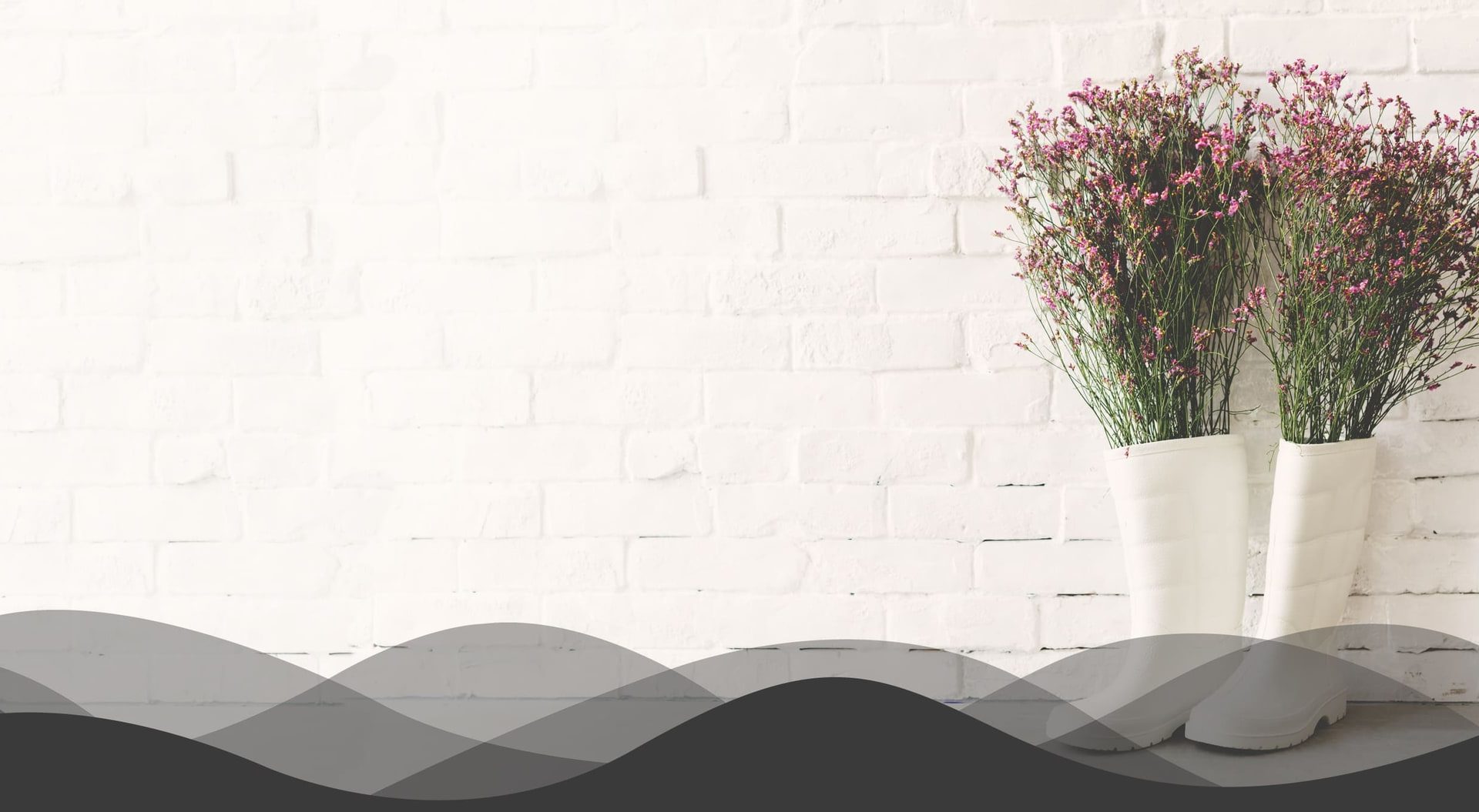 White brick wall with pink flowers in white vases